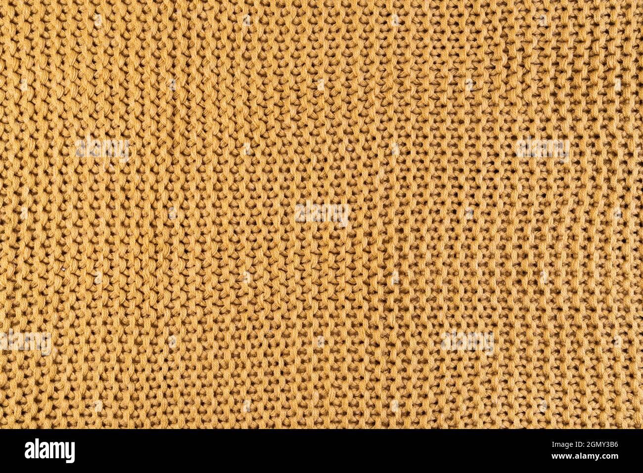 Nahaufnahme von goldfarbenem Strickstoff, textiler Hintergrund Stockfoto