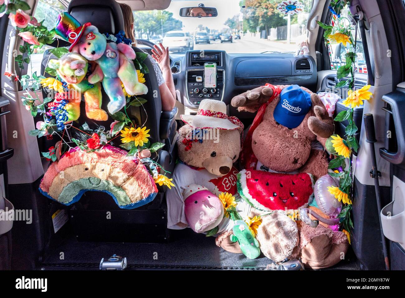 Eine weibliche Uber-Fahrerin mit ihrem barrierefreien Van, der mit Stoffspielzeug dekoriert ist. Sie behauptet, von ihren Kunden positives Feedback erhalten zu haben. Stockfoto