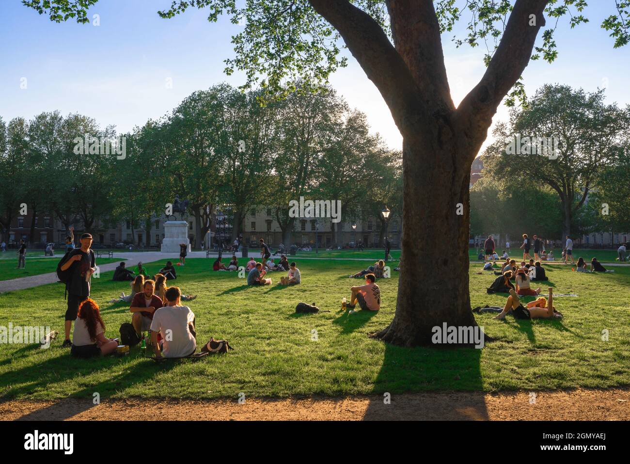 Park Summer People, Blick auf junge Leute, die sich an einem heißen Sommerabend im Queen Square, einem Park im Zentrum der Stadt Bristol, England, entspannen Stockfoto