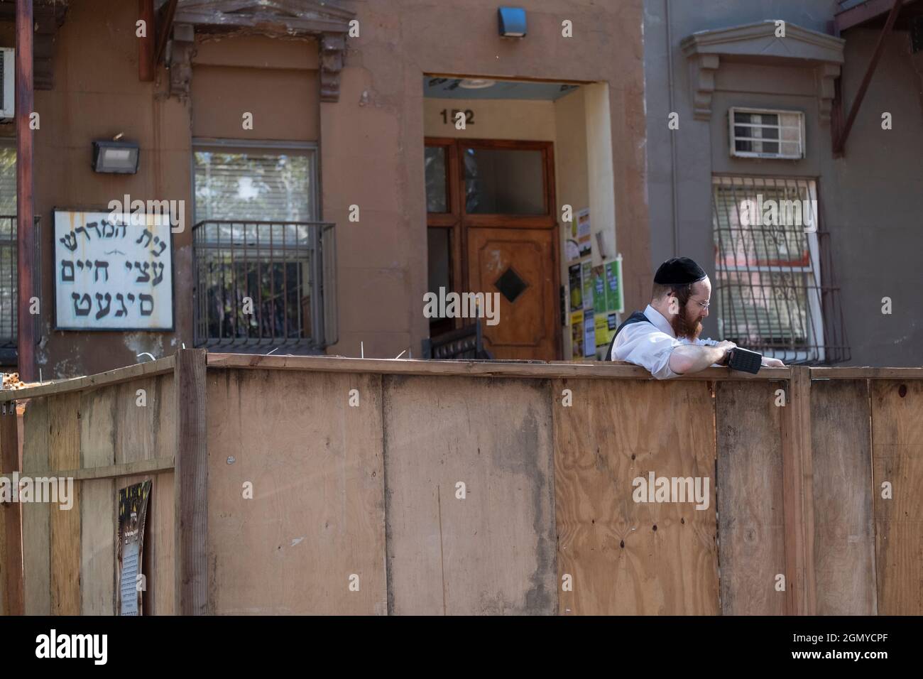 Für den Sukkos-Feiertag baut ein orthodoxer jüdischer Mann mit einer tragbaren Bohrmaschine eine Sukkah vor einer Nachbarschaftssynagoge. In Brooklyn, New York. Stockfoto