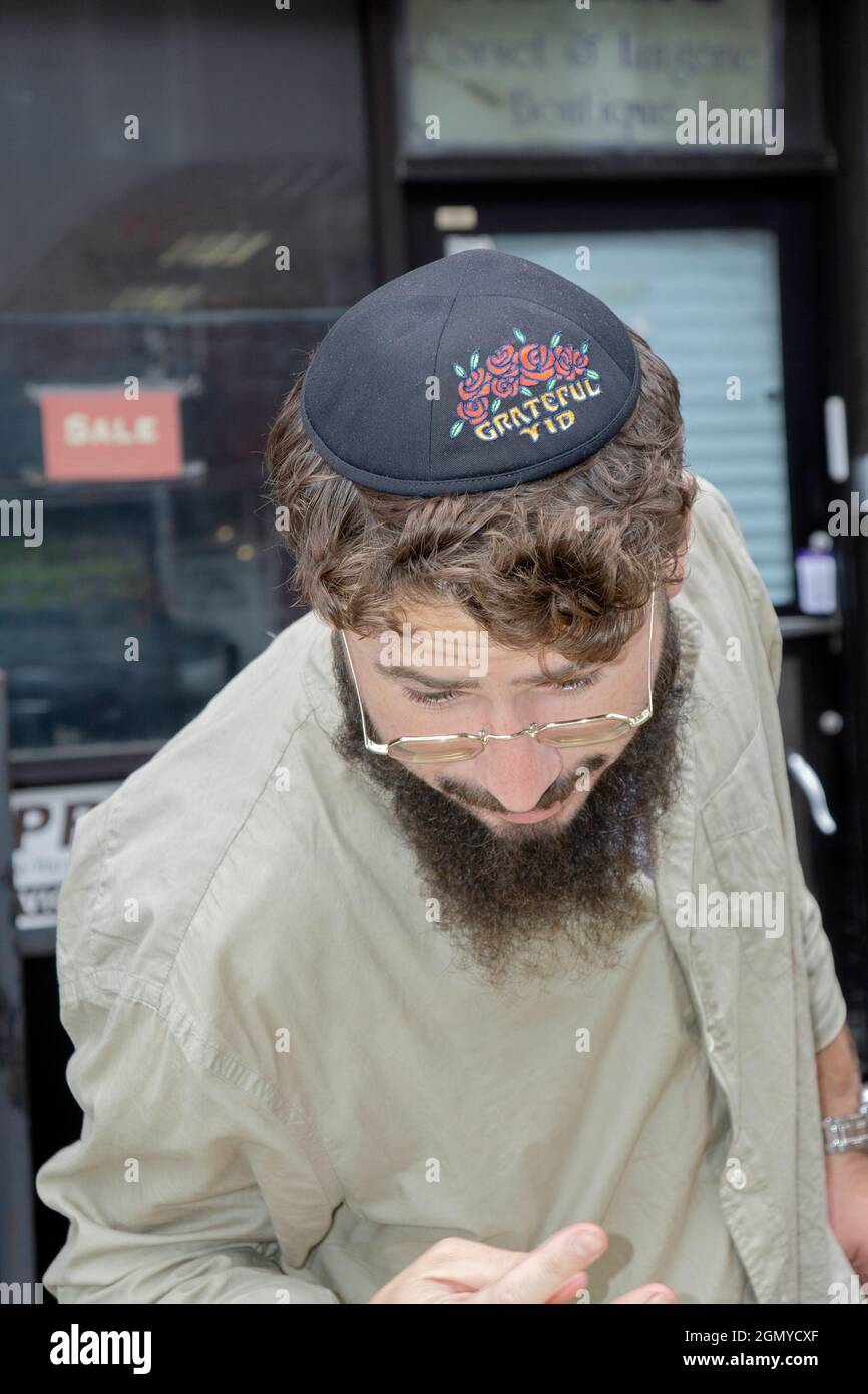 Ein orthodoxer jüdischer Mann trägt eine dankbare Yid-Schädelkappe, die seine Zuneigung zur Grateful Dead-Rockband zum Ausdruck bringt. In Williamsburg, Brooklyn, New York. Stockfoto