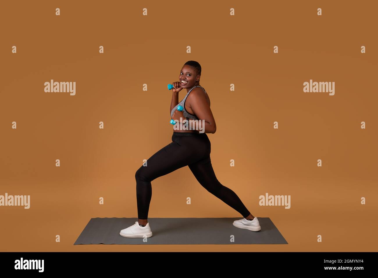 Mollig schwarz Training mit Hanteln auf Yogamatte Stockfoto