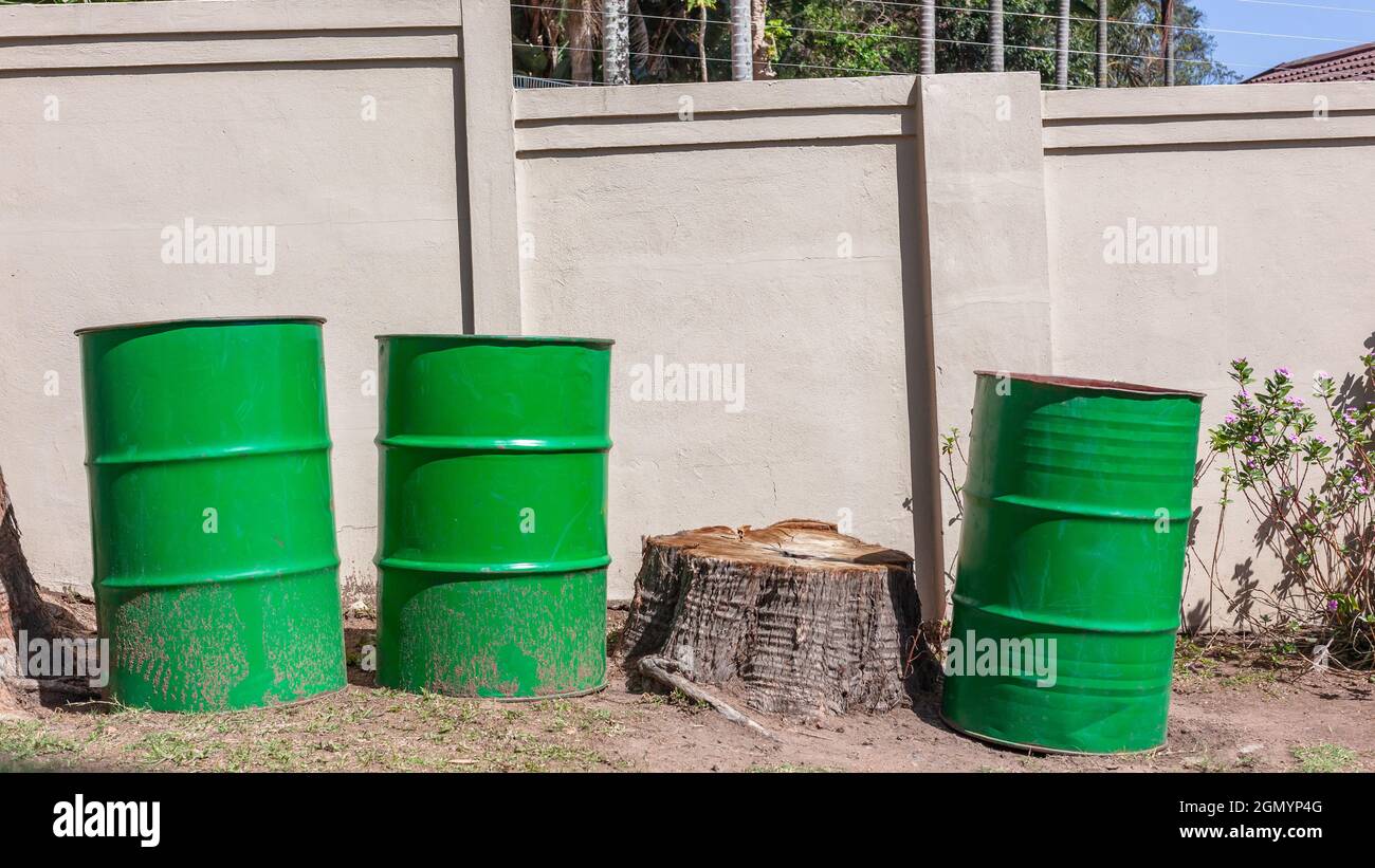 Drei grüne Stahlbehälter oder Fässer aus fünfundvierzig Gallonen oder zweihundert Liter fassenden Metallbehältern oder Fässern, die für die Sammlung von Gartenmüll am Straßenrand verwendet werden. Stockfoto