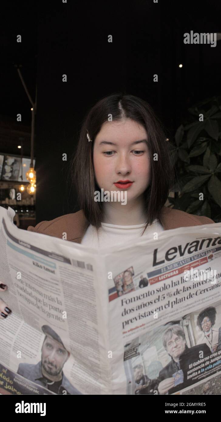 Junge Frau beim Lesen der Zeitung beim Frühstück in einer Cafeteria. Autumn Vibes Concept 2021. Stockfoto