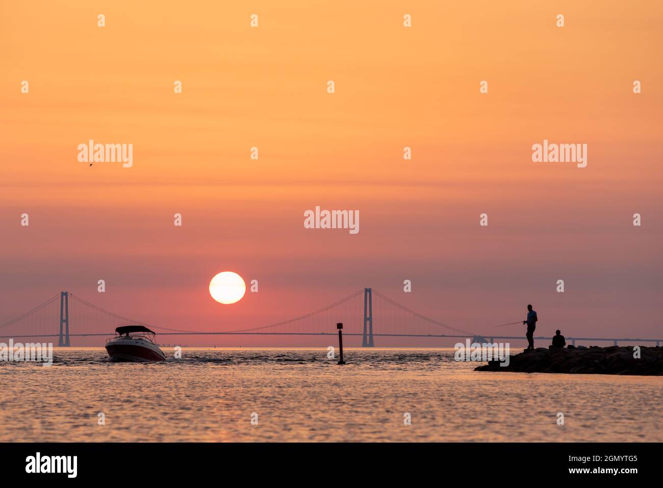 Silhouette von zwei Männern, die mit der Großen Gürtelbrücke im Hintergrund fischen, Dänemark Stockfoto