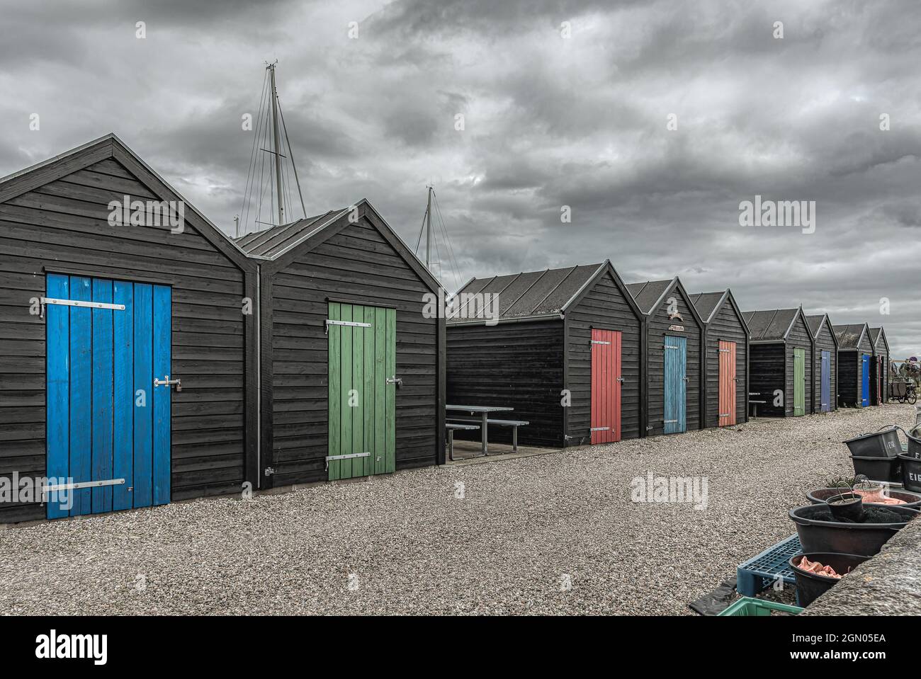 Fischersteaus´s Reihen sich auf einer Schotterstraße mit Türen in hellen Farben auf, Åarøsund, Dänemark, 26. August 2021 Stockfoto