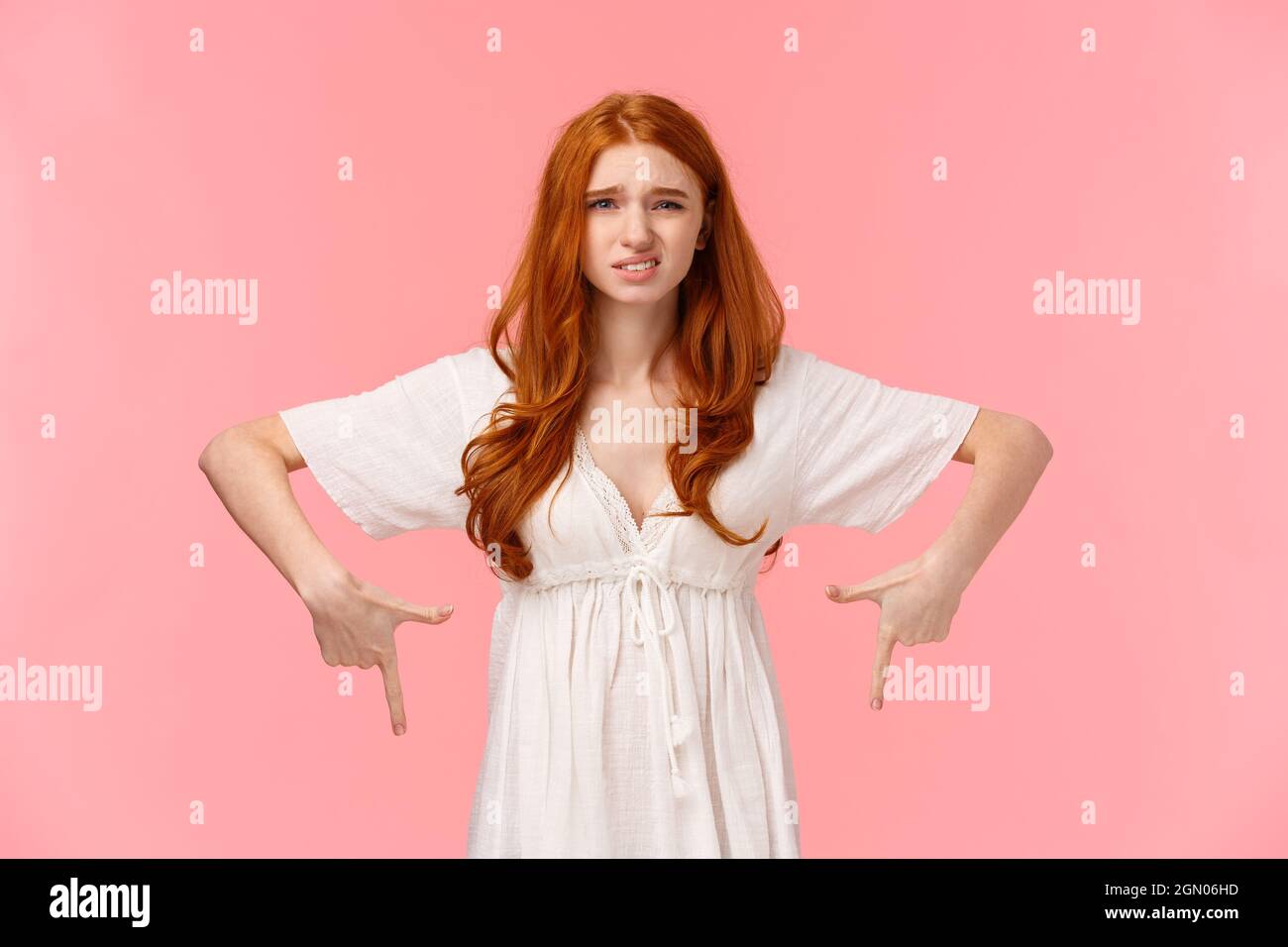 Nun, ich weiß es nicht. Taille-up Porträt unentschlossen und unsicher, etwas unzufrieden nette Rothaarige Frau in weißem Kleid, zeigt nach unten, cringe als Express DIS Stockfoto