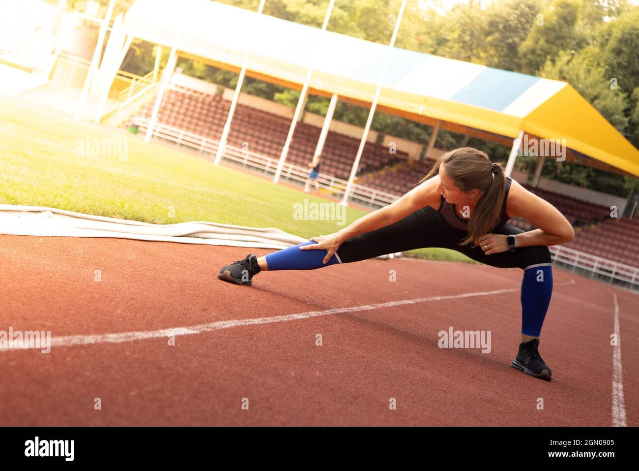 Junge athletische Frau streckt und bereitet sich auf das Laufen vor. Starke Sportfrau Stockfoto