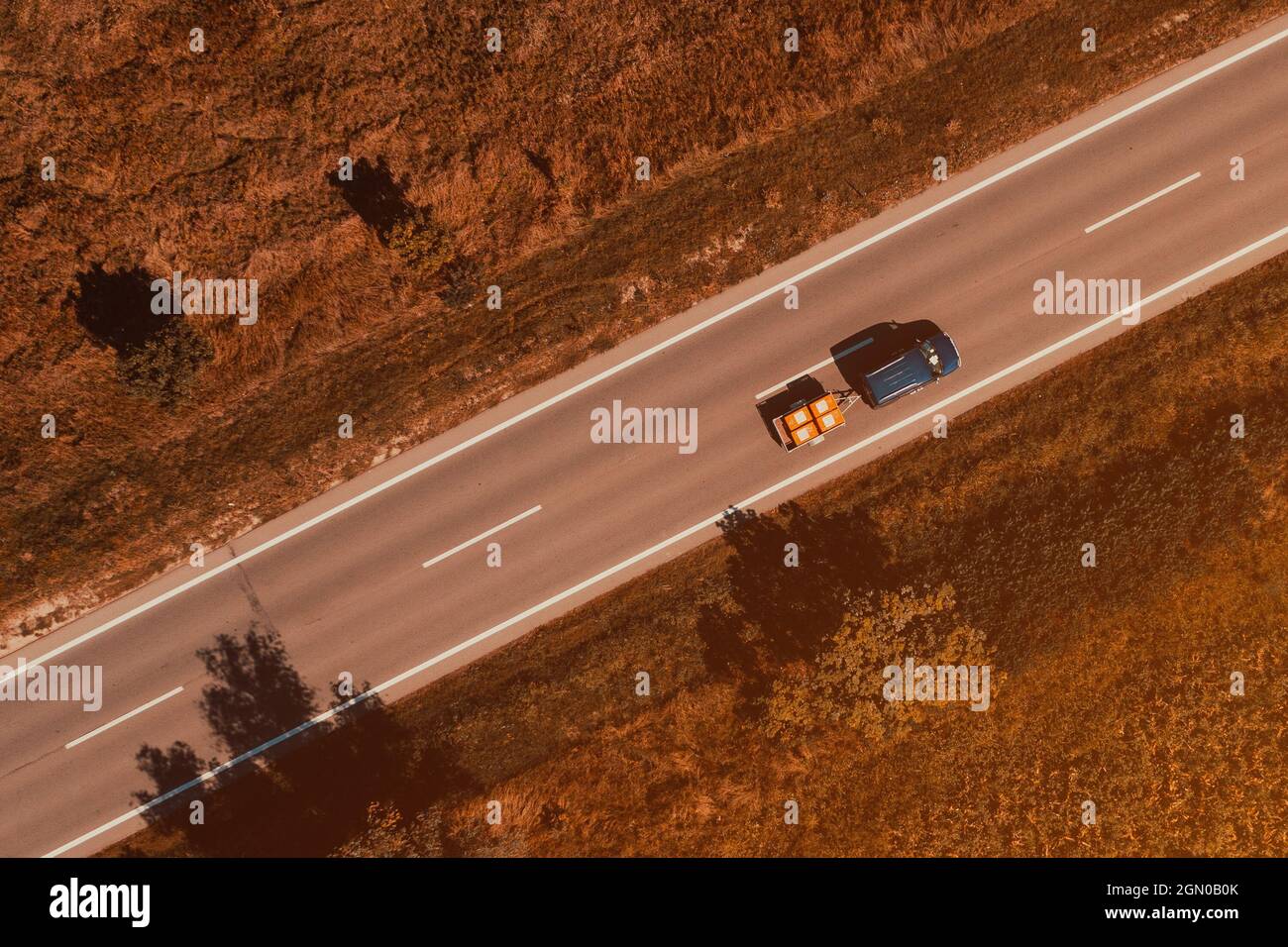 Luftaufnahme eines Fahrzeugs mit Anhänger, der die Straße entlang fährt, Drohnenfotografie aus der Perspektive von oben nach unten Stockfoto