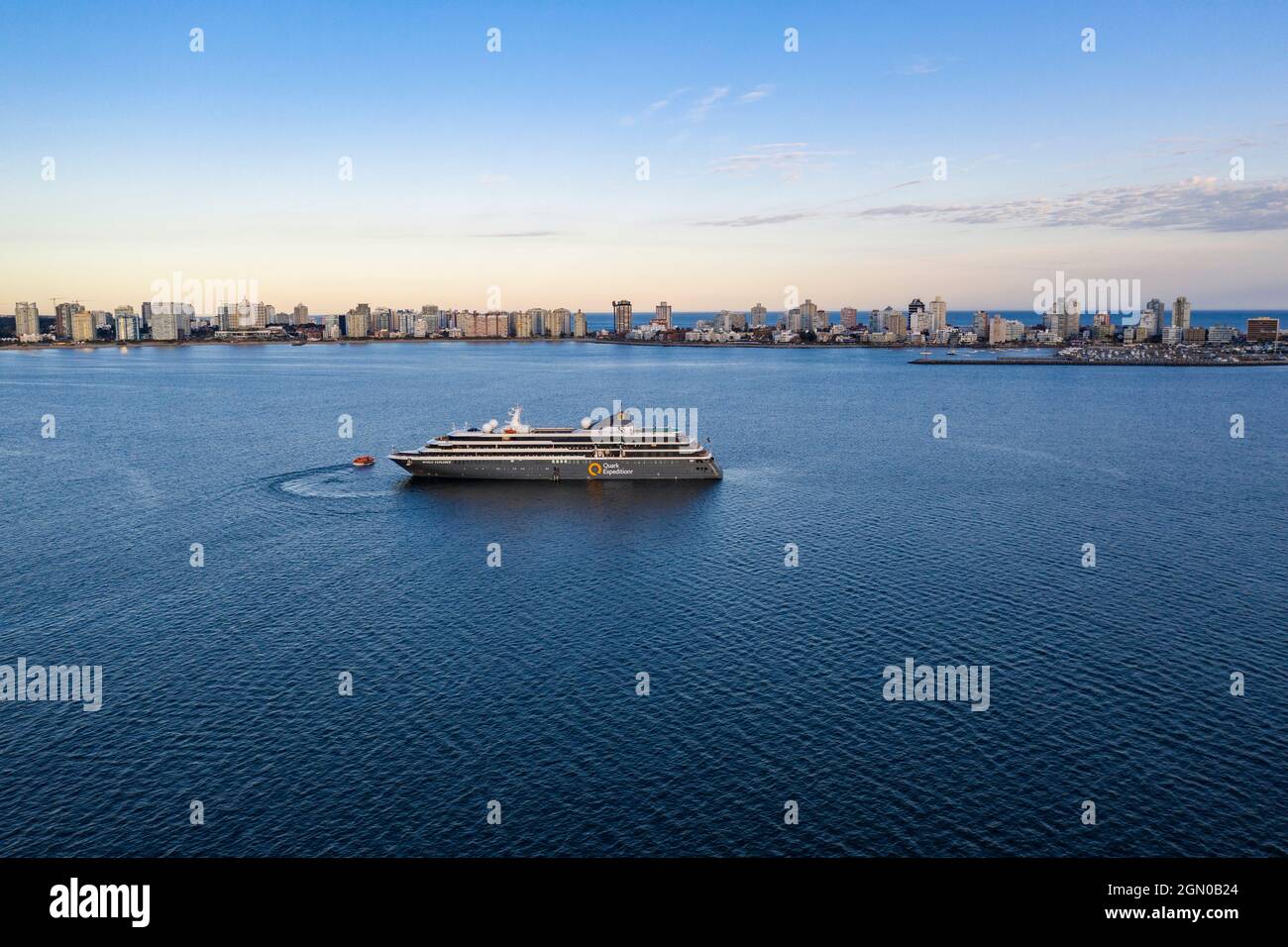 Luftaufnahme des Expeditionskreuzfahrtschiffes World Explorer (Nicko Cruises) mit Skyline der Stadt bei Sonnenuntergang, Punta del Este, Maldonado Department, Uruguay Stockfoto