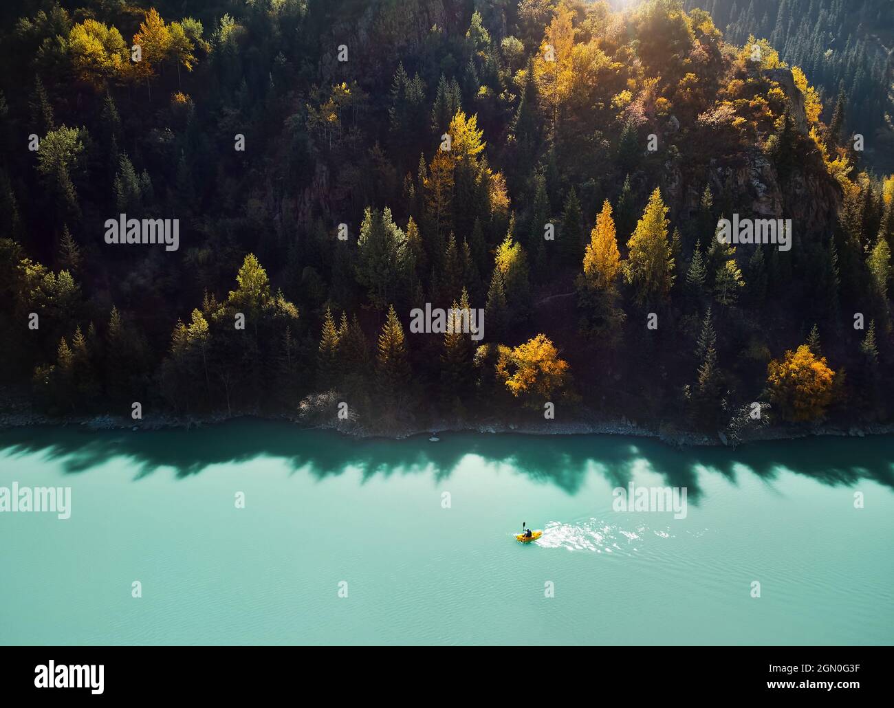 Im Herbst paddelt der Mensch auf einem gelben Floßboot im Bergsee. Luftdrohnenaufnahme. Stockfoto