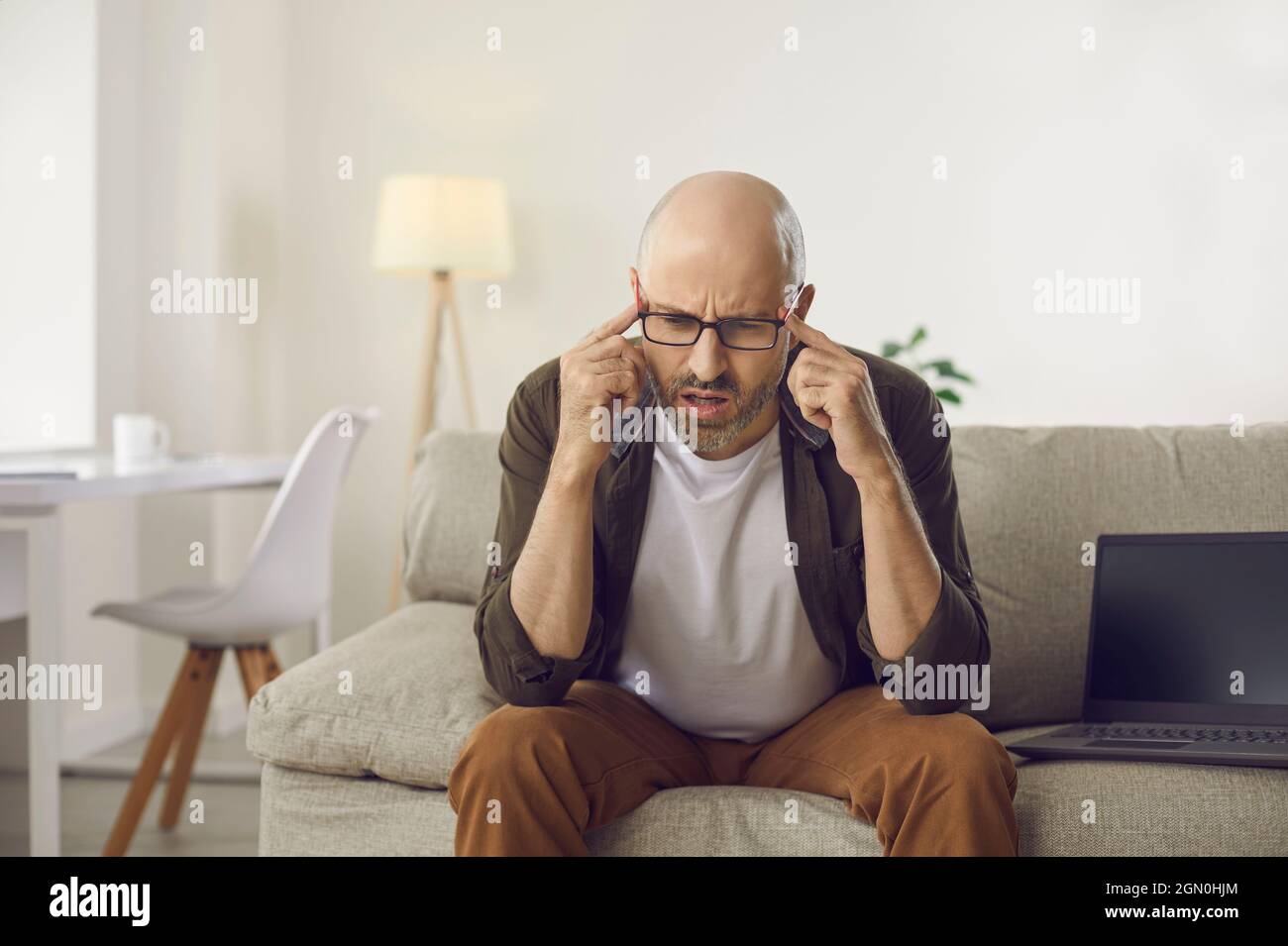 Verwirrt Mann auf dem Sofa sitzen und hart denken versuchen, Problem zu verstehen oder Frage zu beantworten Stockfoto