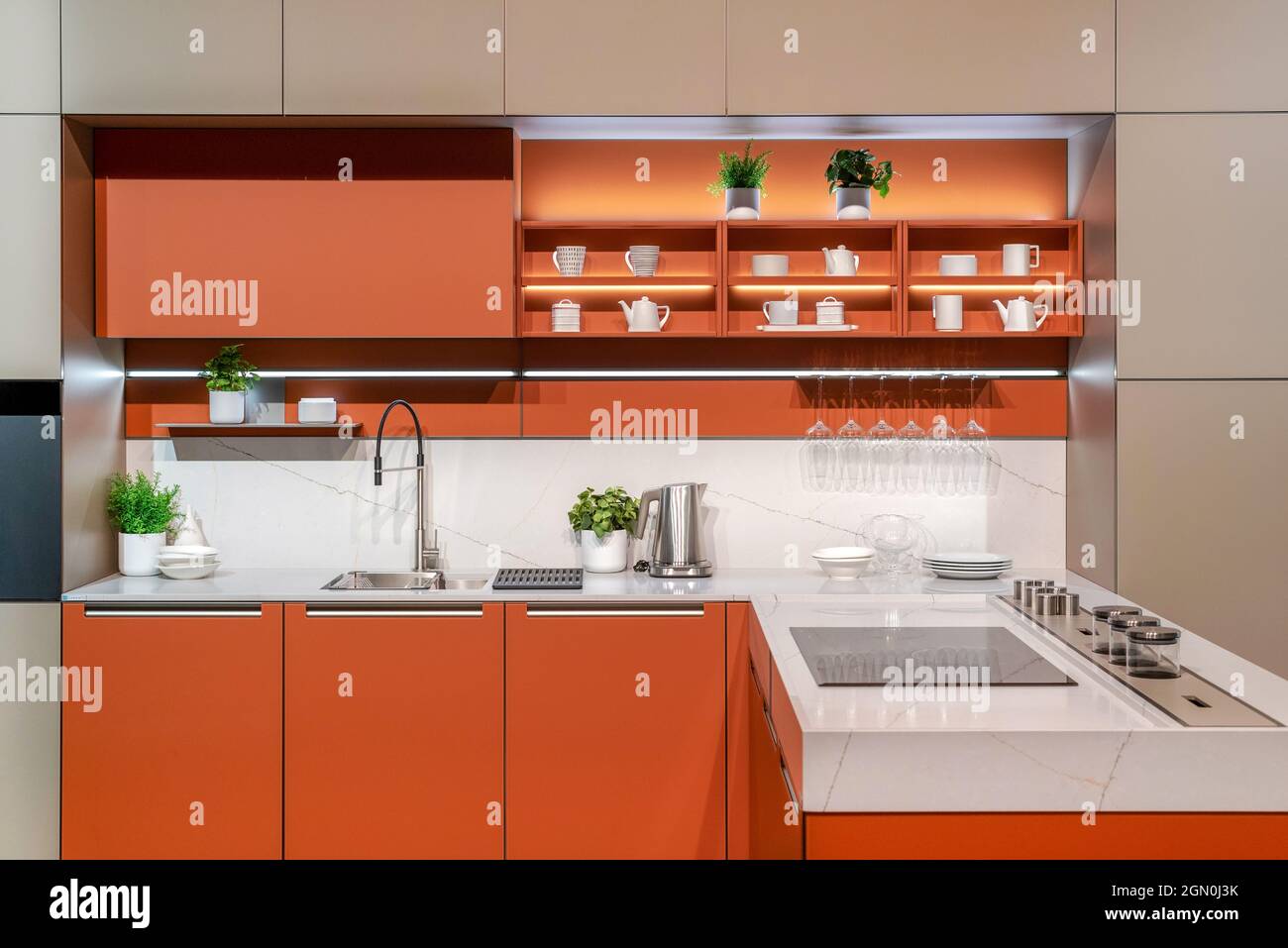 Moderne Einrichtung von Küchengeräten und Schränken in minimalistischem Stil in orangefarbener Farbe Stockfoto