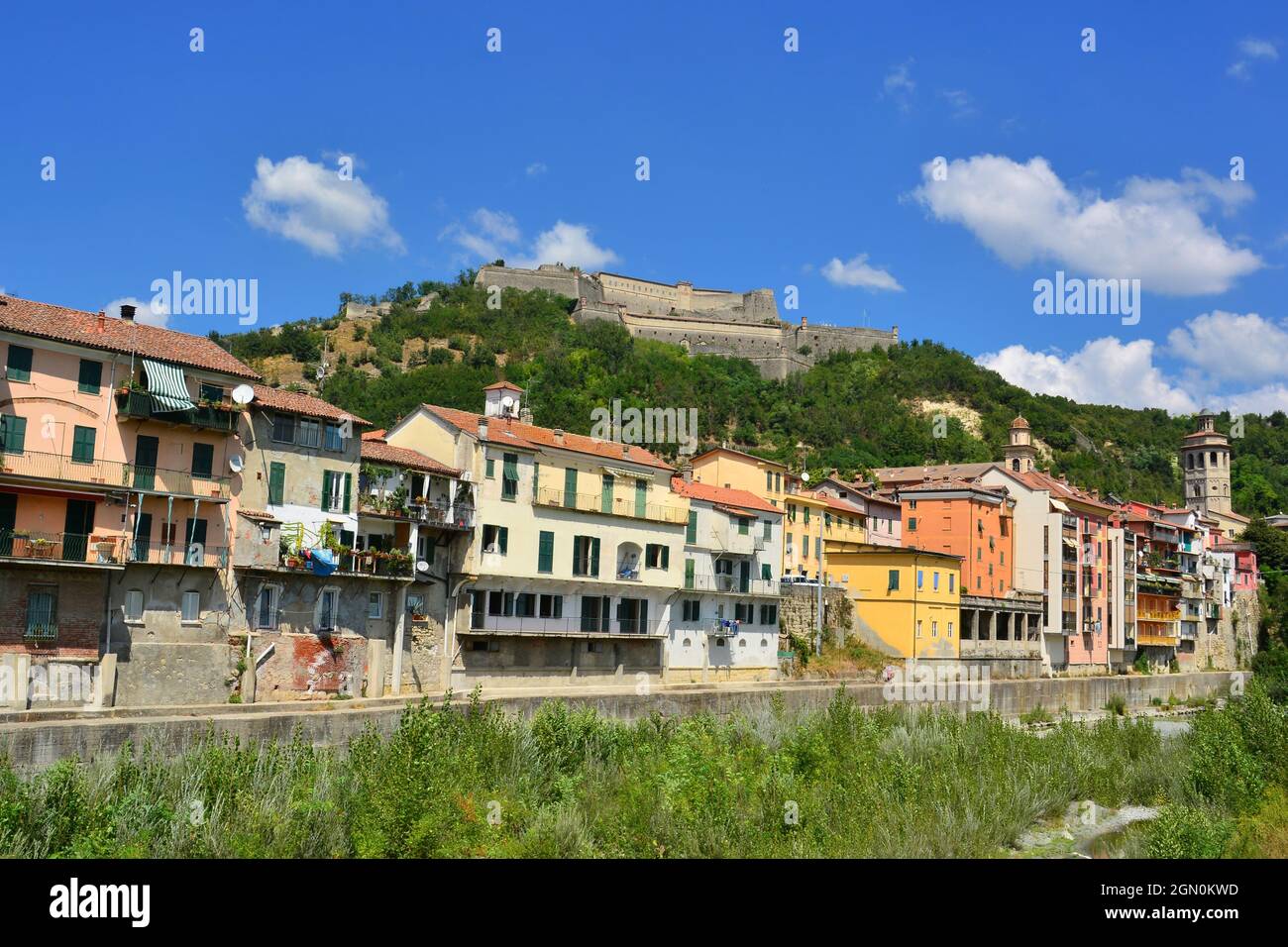 Gavi, Alessandria, Piemonte, Italia. Blick auf das Dorf Gavi, berühmt für seine berühmten Weine, und das Fort von einer Brücke auf dem Lemme Creek. Stockfoto