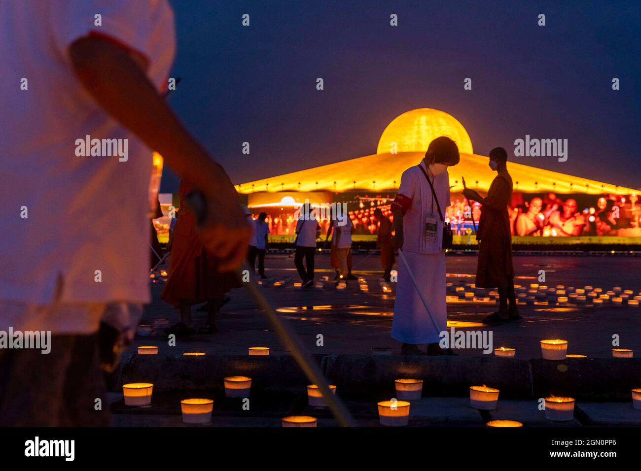 Patum Thani, Pathum Thani, Thailand. September 2021. Wat Dhammaya, bekannt für seine einzigartige Tempelkonstruktion und spirituelle Lehre, hielt eine Zeremonie anlässlich des Internationalen Tages des Friedens ab, der 1981 von den Vereinten Nationen als Tag der Waffenruhe und Gewaltlosigkeit gegründet wurde. Der Tempel organisierte eine Ausstellung von über 200,000 Kerzen und LED-Lichtern, um vom Himmel aus sichtbare Muster zu bilden, die verschiedene Phasen im Leben des verstorbenen Meditationsmeisters Luang Pu Sodh Candasaro des Tempels darstellen. Tausende von Menschen nahmen per Zoom-Anruf aus der Ferne an der Zeremonie Teil, wobei ihre Video-Feeds auf l angezeigt wurden Stockfoto