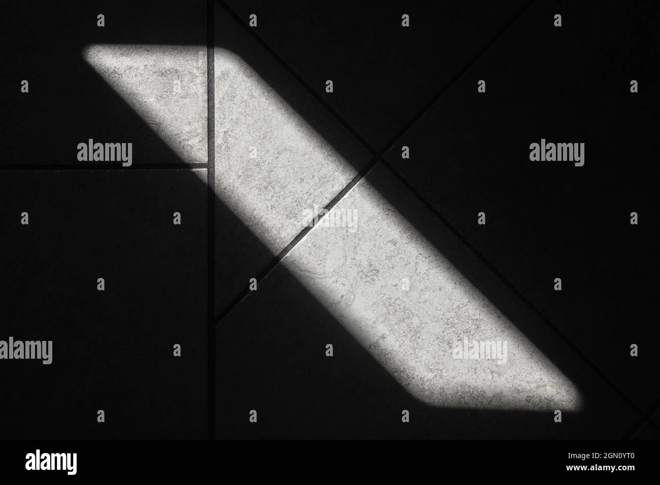 Abstraktes Innenraumbild, Sonnenstrahl auf dunklen Bodenflieren, Draufsicht Stockfoto