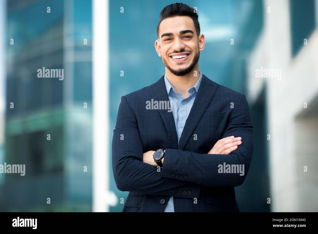 Wohlhabender mittelöstlicher Geschäftsmann, der neben dem Bürogebäude posiert Stockfoto