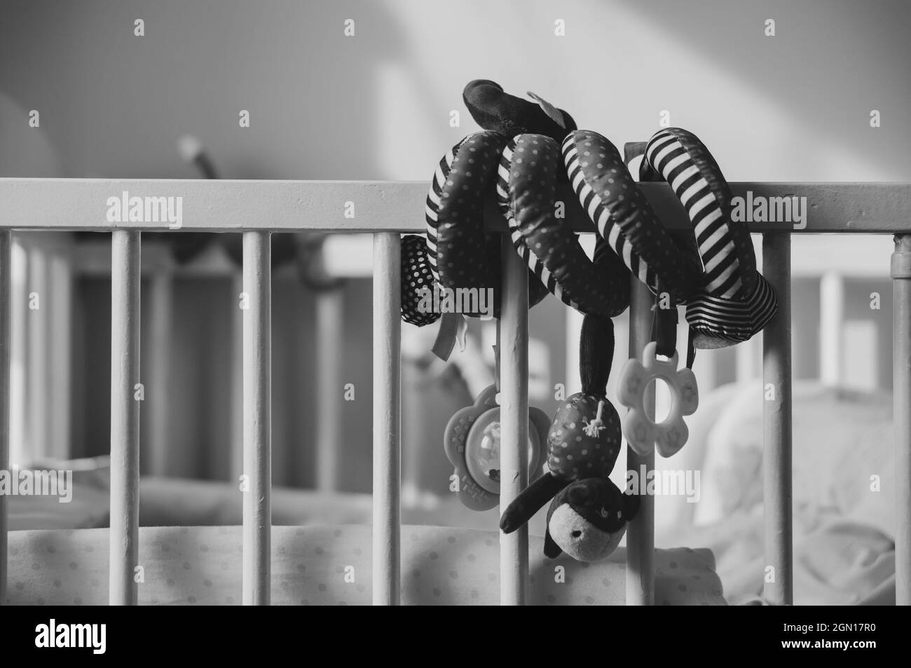 Graustufen-Aufnahme von spiralförmigen Babyspielzeug auf einer Krippe Stockfoto