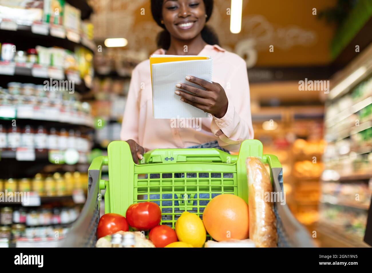 African American Lady Reading Einkaufsliste Zu Fuß Im Supermarkt Stockfoto