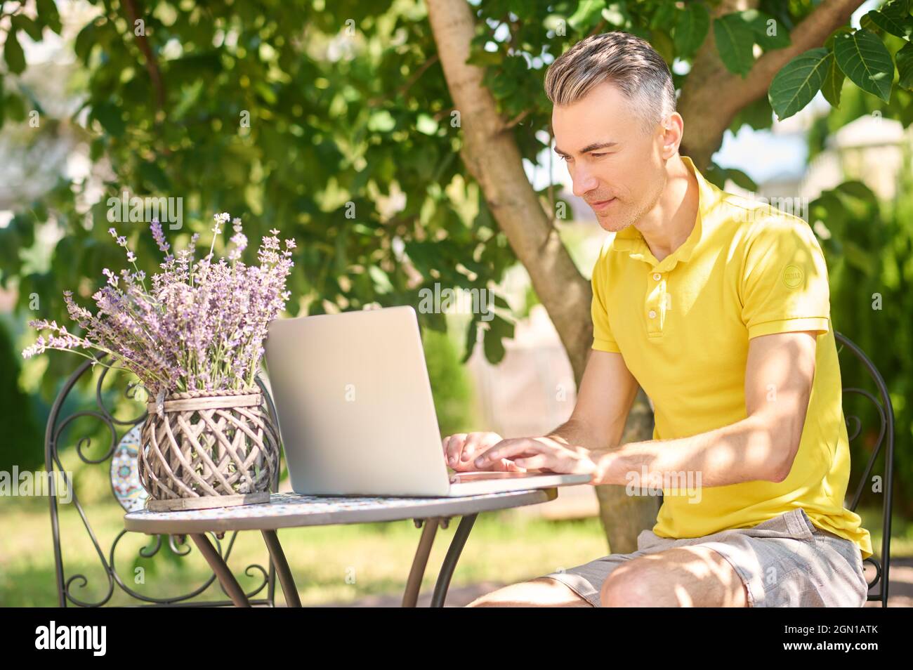 Mann, der zu Hause im Garten am Laptop arbeitet Stockfoto