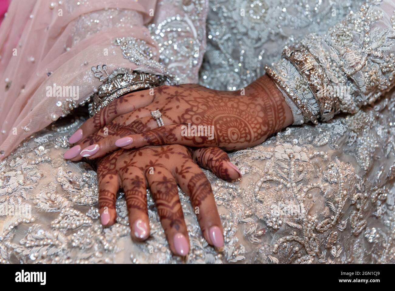 Die schönen Hände der Hindu-Braut sind mit traditioneller Mehndi Henna-Tattoo-Kunst, Maniküre und Diamantring verziert. Stockfoto