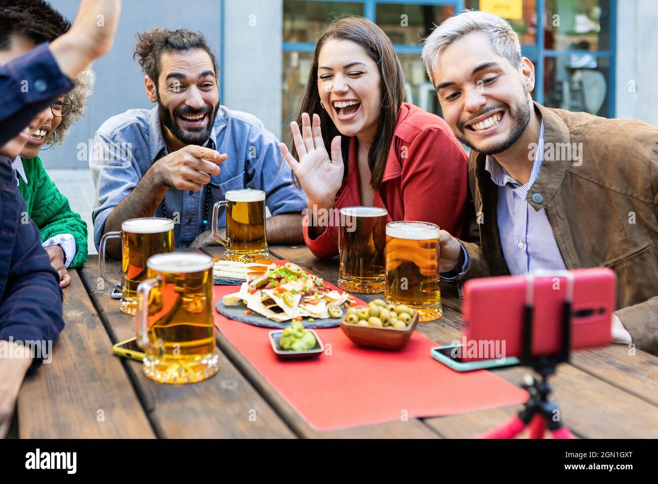 Eine Gruppe junger Leute, die lachen und einen Videoanruf auf dem Handy in der Brauerei-Bar machen Stockfoto