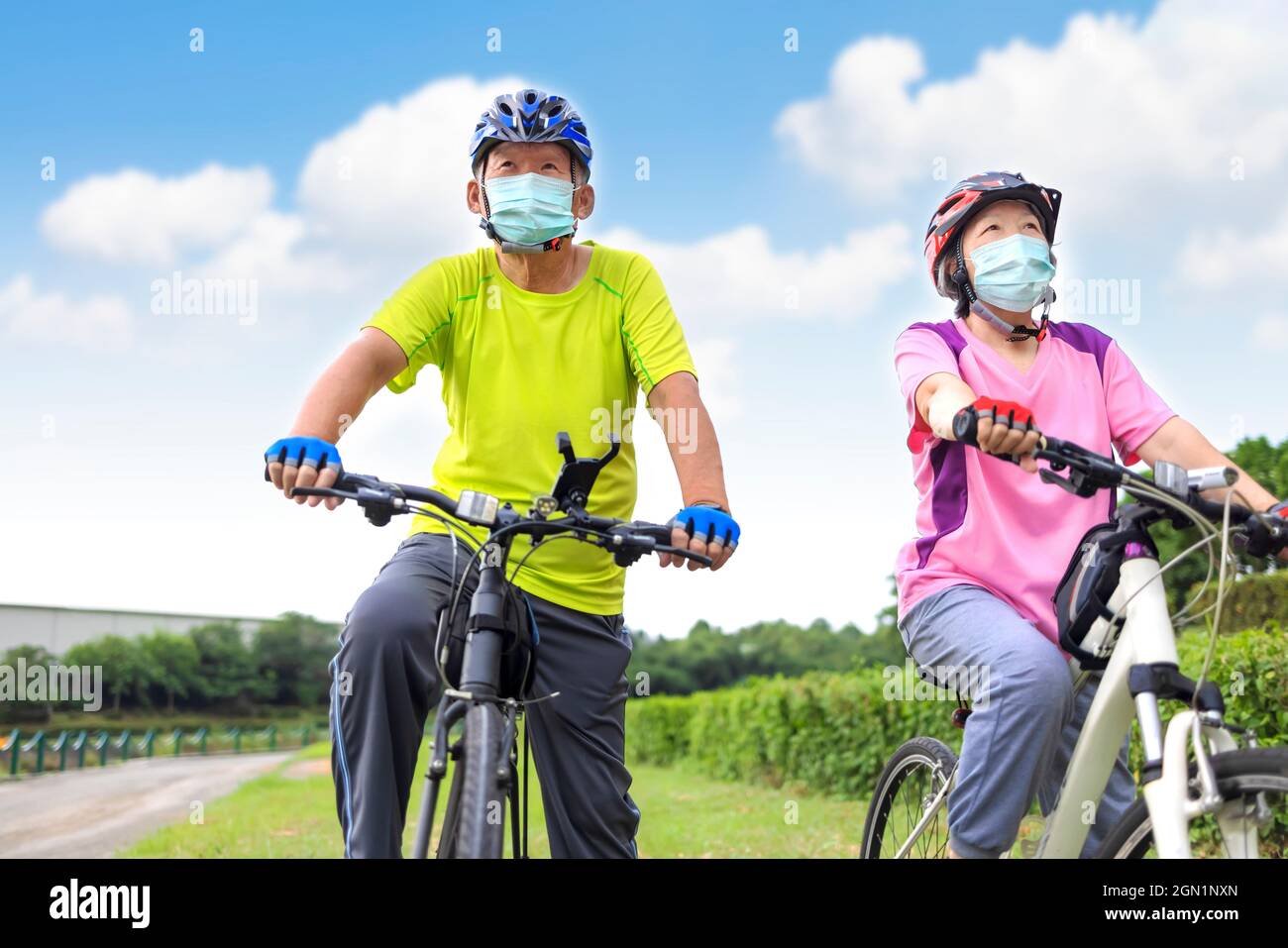 Asian Senior paar trägt medizinische Maske und Fahrrad im Park fahren Stockfoto