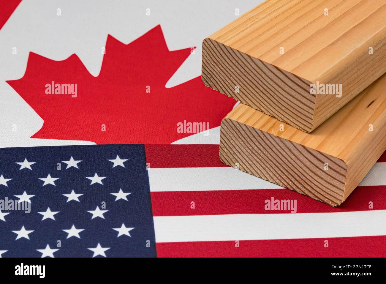 Weichholz Bauholz unter der Flagge von Kanada und den Vereinigten Staaten von Amerika. Handelskrieg, Zölle, fairer Handel und Holz, Holzwirtschaft Konzept Stockfoto