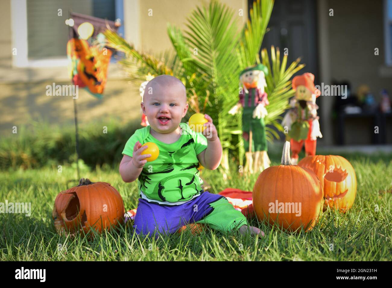 Kind auf Rasen mit Kürbissen an halloween im Kostüm Stockfoto