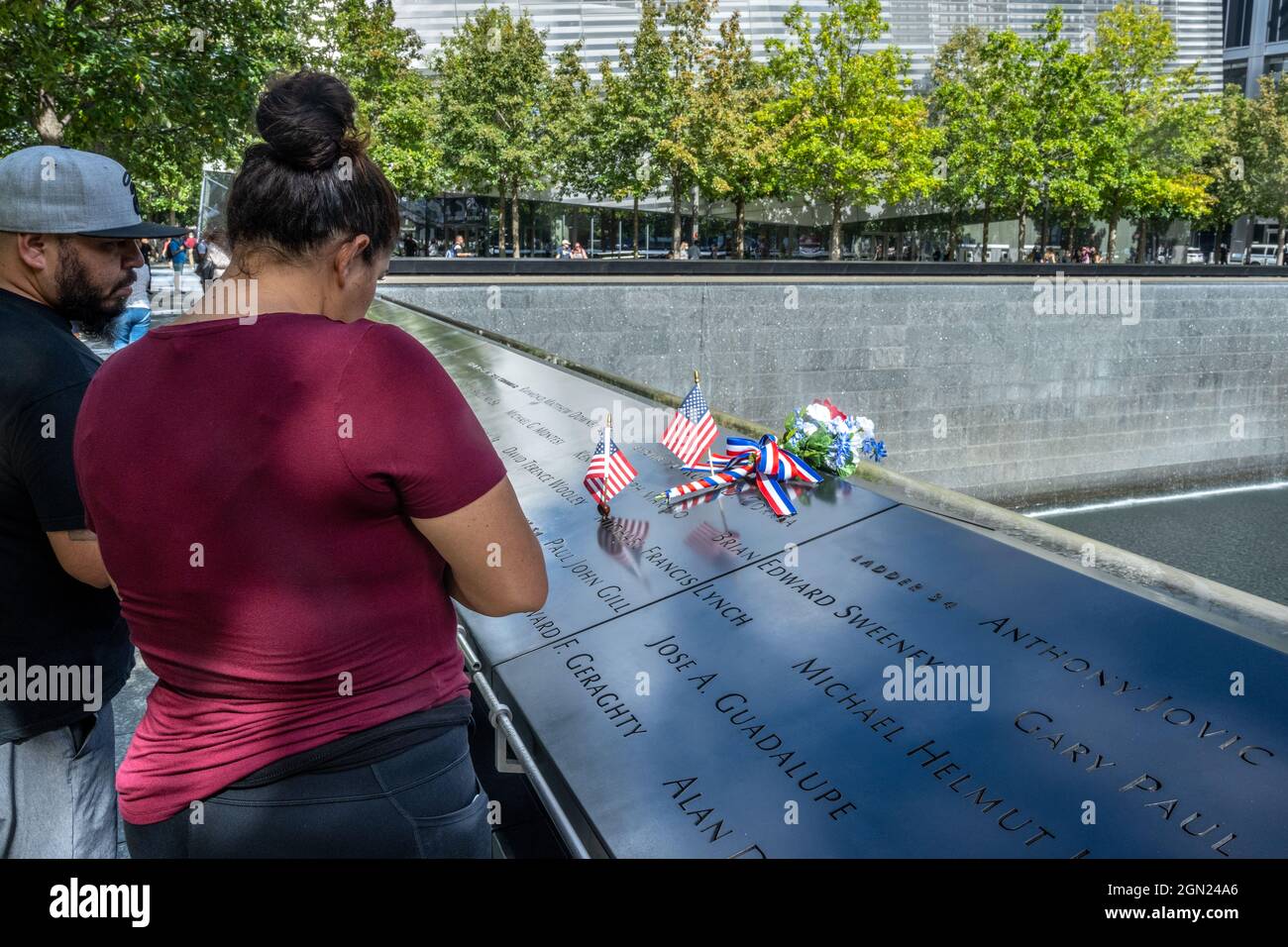 New York, USA, 21. September 2021 - US-Flaggen und Blumen sind neben den Namen der Opfer des Terroranschlags auf der National September 11 Memoria zu sehen Stockfoto