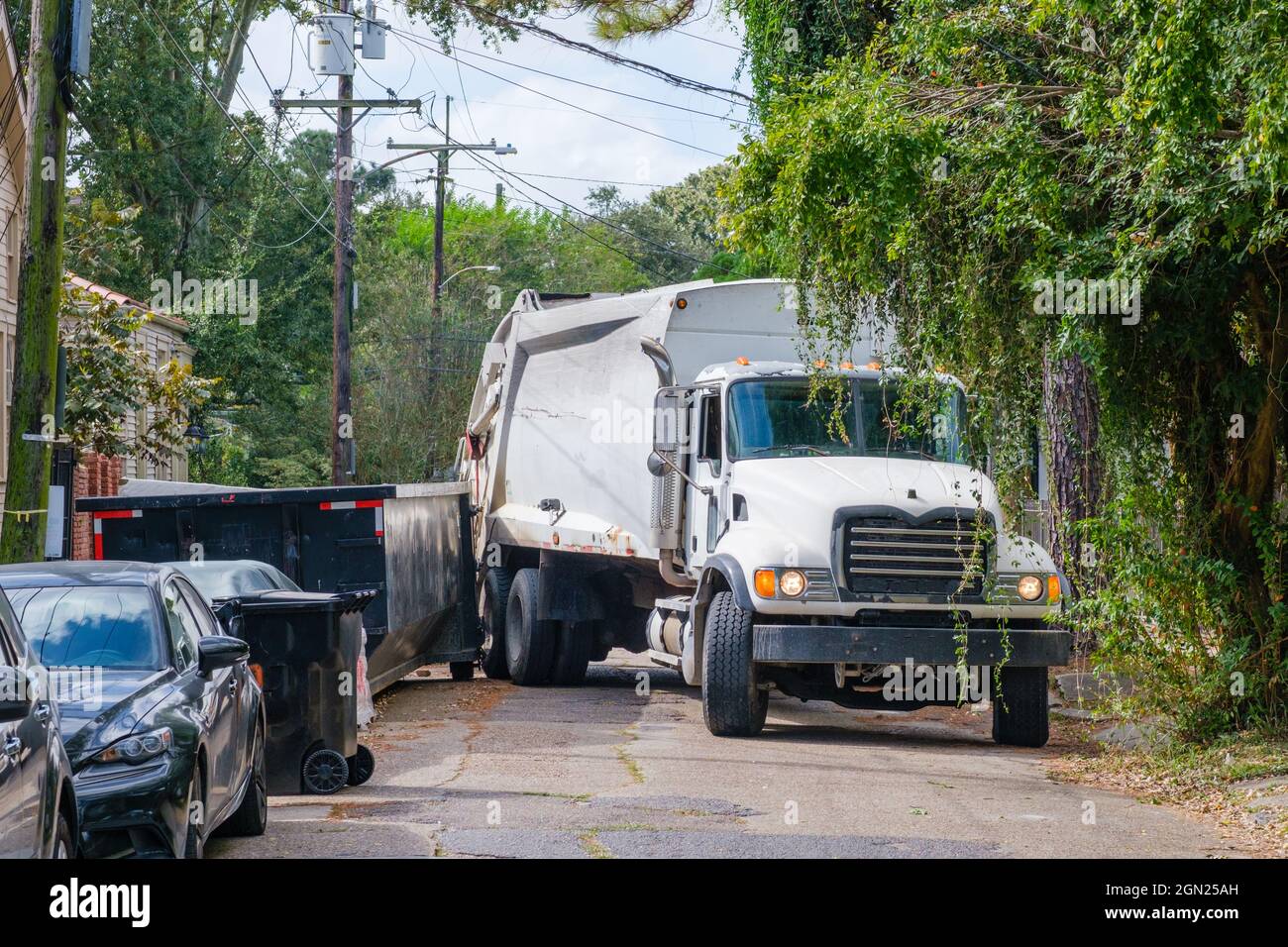 NEW ORLEANS, LA - 21. OKTOBER 2020: Ein Sanitär-LKW steckt zwischen einem Müllcontainer und einem geparkten Auto in einem Uptown-Viertel Stockfoto