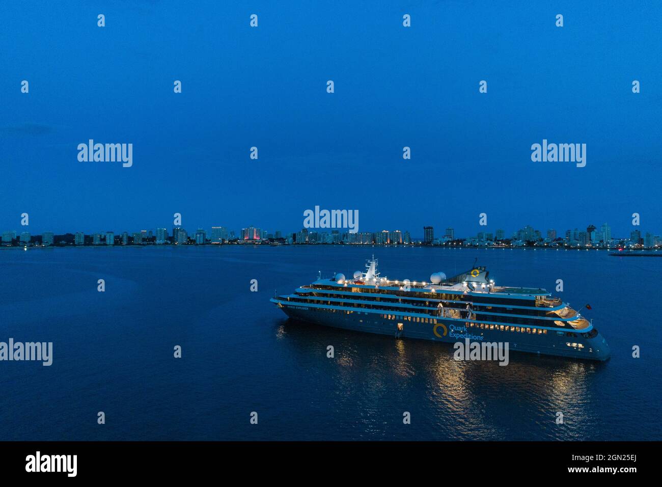 Luftaufnahme des Expeditionskreuzfahrtschiffes World Explorer (Nicko Cruises) mit der Skyline der Stadt in der Abenddämmerung, Punta del Este, Maldonado Department, Uruguay, Stockfoto