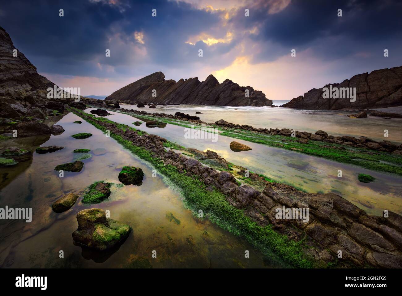 SPANIEN, KANTABRIEN, LIENCROS. ALLGEMEINER BLICK AUF PLAYA DEL MANDERO BEI SONNENUNTERGANG UND UNTER STÜRMISCHEM HIMMEL Stockfoto