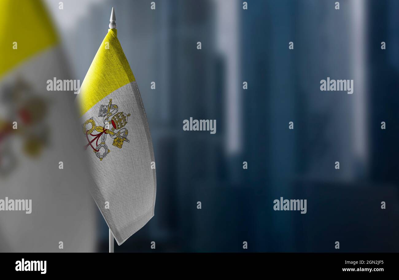 Kleine Fahnen des Vatikans auf einem verschwommenen Hintergrund der Stadt Stockfoto