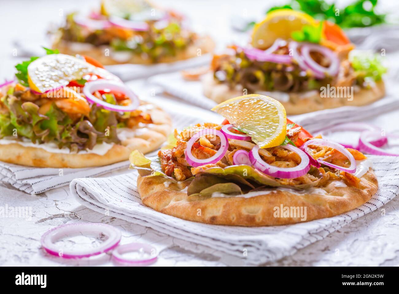 Griechisches Gyros-Fleisch mit Pita-Fladenbrot, Gemüse und Zwiebeln und Tzatziki-Dip auf weißem Hintergrund Stockfoto