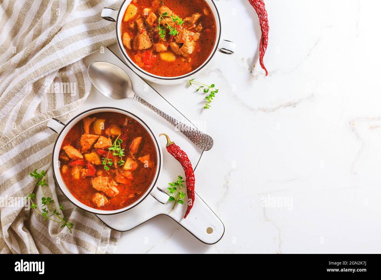 Rindergulaschsuppe – herzhafte ungarische Suppe mit Fleisch und Gemüse, gewürzt mit Paprika auf weißem Hintergrund Stockfoto