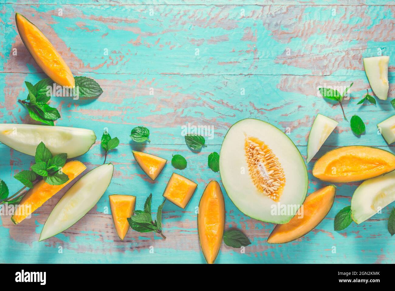 Gesunder Snack - Piel de Sapo Melone und Cantaloupe mit frischer Minze auf dem cyanfarbenen Holztisch Stockfoto
