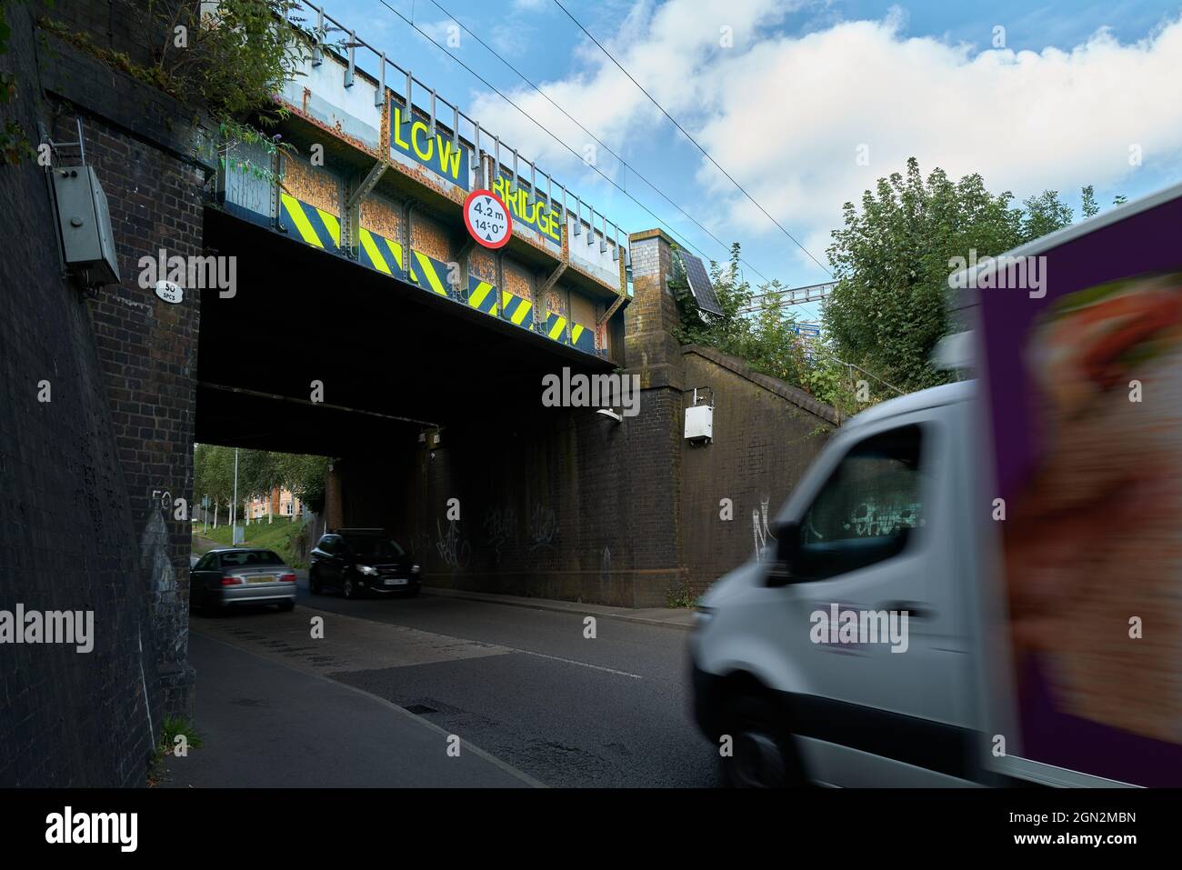 Niedrige Eisenbahnbrücke über die Straße. Stockfoto