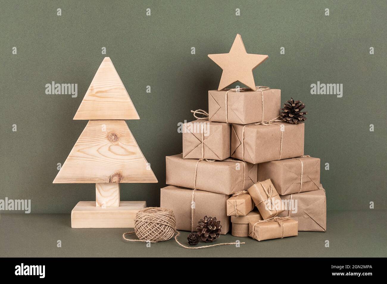Komposition zu Weihnachten oder Neujahr. Hausgemachter Weihnachtsbaum aus Holz, viel Geschenk, Urlaubsdekor auf grünem Hintergrund. Konzept weihnachten Null Abfall, umweltfreundlich Stockfoto