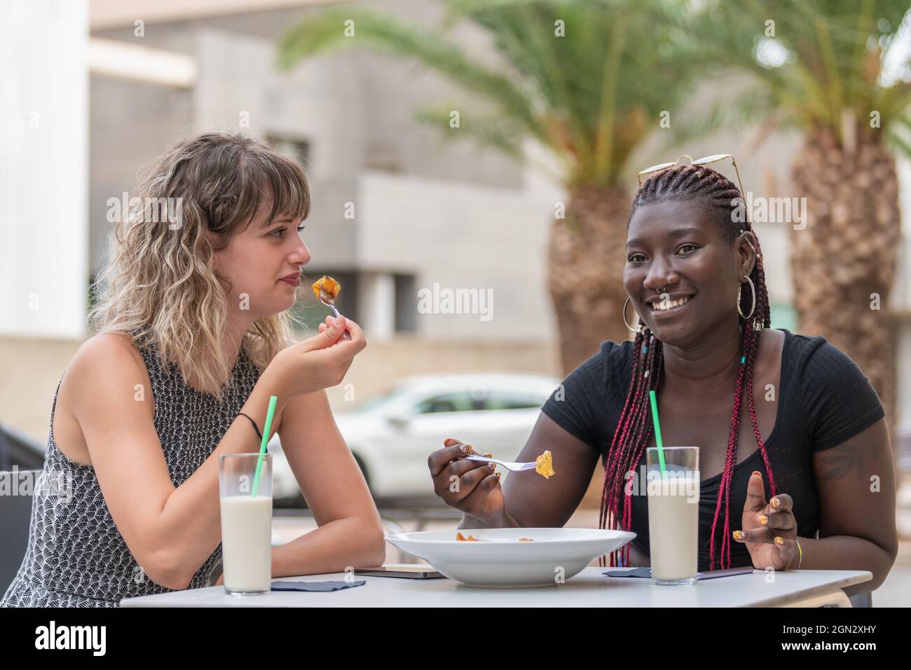 Zwei Frauen, die in einem Café im Freien essen und trinken, haben eine gute Zeit Stockfoto