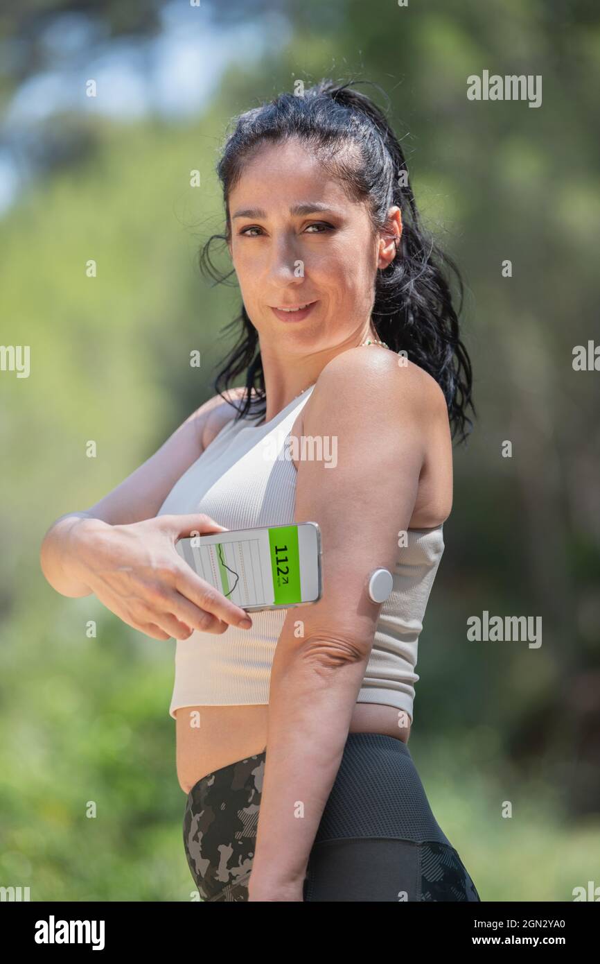 Diabetische Frau demonstriert Glucose-Überwachung und -Kontrolle mit Fernsensor und Smartphone Stockfoto