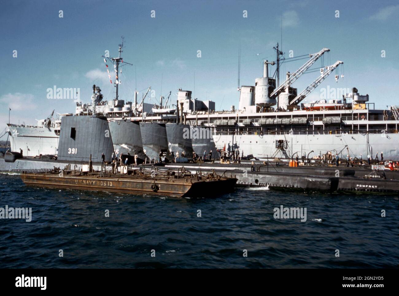 Eine geschäftige Szene der US Navy an den Docks in San Diego, Kalifornien, USA im Jahr 1960. Fünf U-Boote sind aufgereiht. Das nächste ist USS Pomfret (SS-391), ein U-Boot der Balao-Klasse, benannt nach dem Pomfret, einem Fisch der Seabream-Familie, einem mächtigen und schnellen Schwimmer. Pomfret wurde 1943 auf der Portsmouth Navy Yard, Kittery, Maine, USA, ins Leben gerufen und im nächsten Jahr in Betrieb genommen. Hinter den U-Booten ist ein Marinestützer zu sehen. Dieses Bild stammt von einem alten Kodak-Amateurfotograf mit Farbtransparenz – einem alten Foto aus den 1960er Jahren. Stockfoto