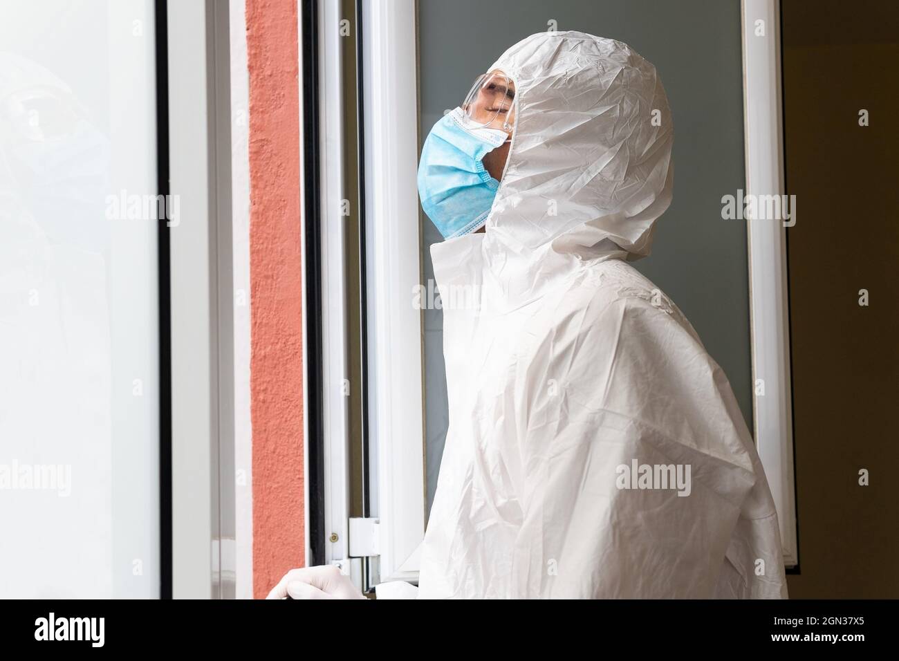 Seitenansicht eines erwachsenen männlichen Mediziners in persönlicher Schutzausrüstung mit geschlossenen Augen, die im Krankenhaus frische Luft atmen Stockfoto