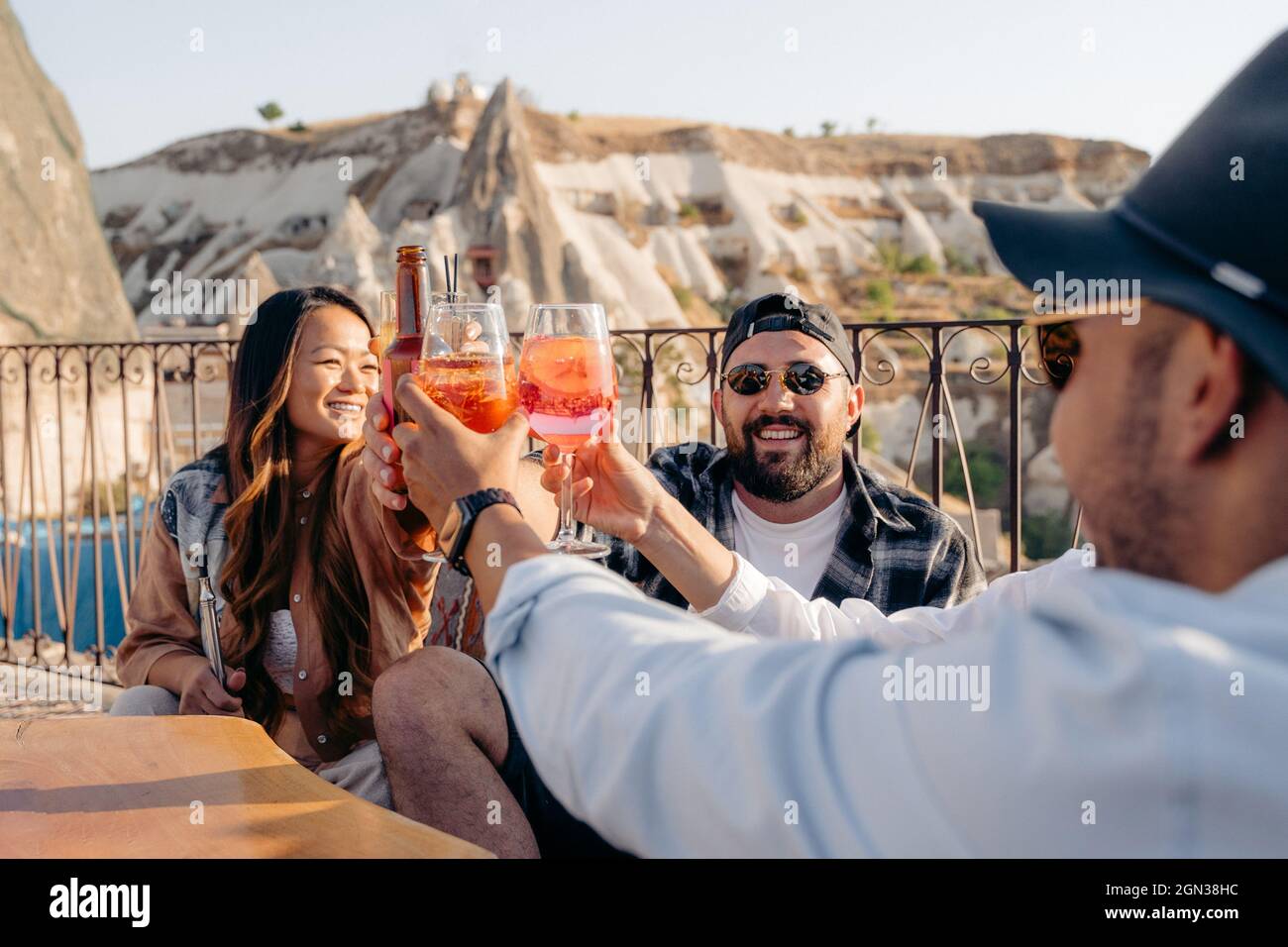 Lächelnde Freunde, die am Tisch sitzen und Gläser mit Cocktails heben, während sie in der Bar abhängen Stockfoto