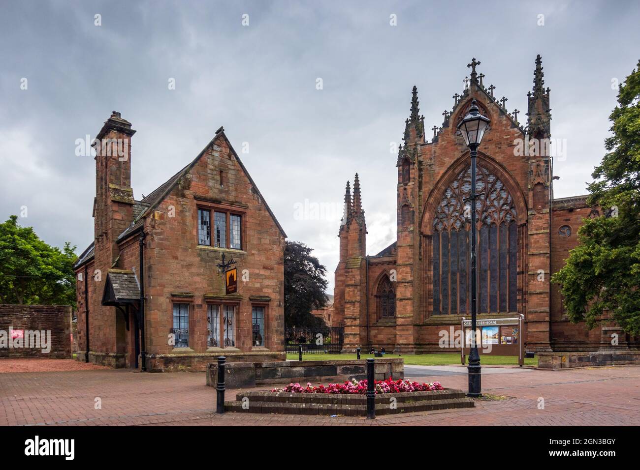 Kathedrale von Carlisle (die Kathedrale der Heiligen und ungeteilten Dreifaltigkeit) mit Cathedral Lodge Antiques auf der linken Seite. Cumbria, England, Großbritannien Stockfoto