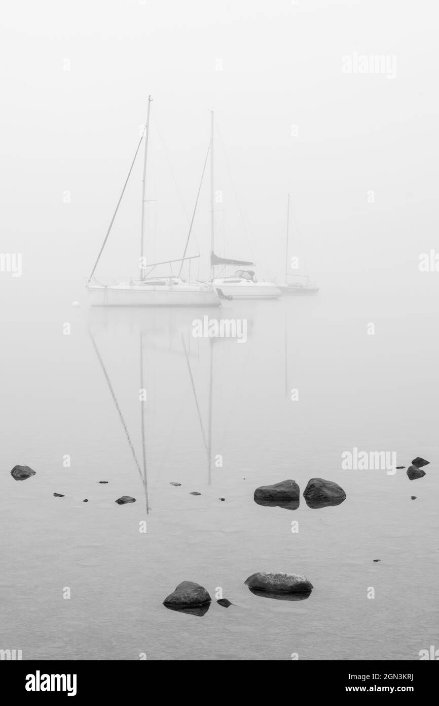 Geisterhafte Yacht-Reflexionen im Nebel auf Windermere Stockfoto