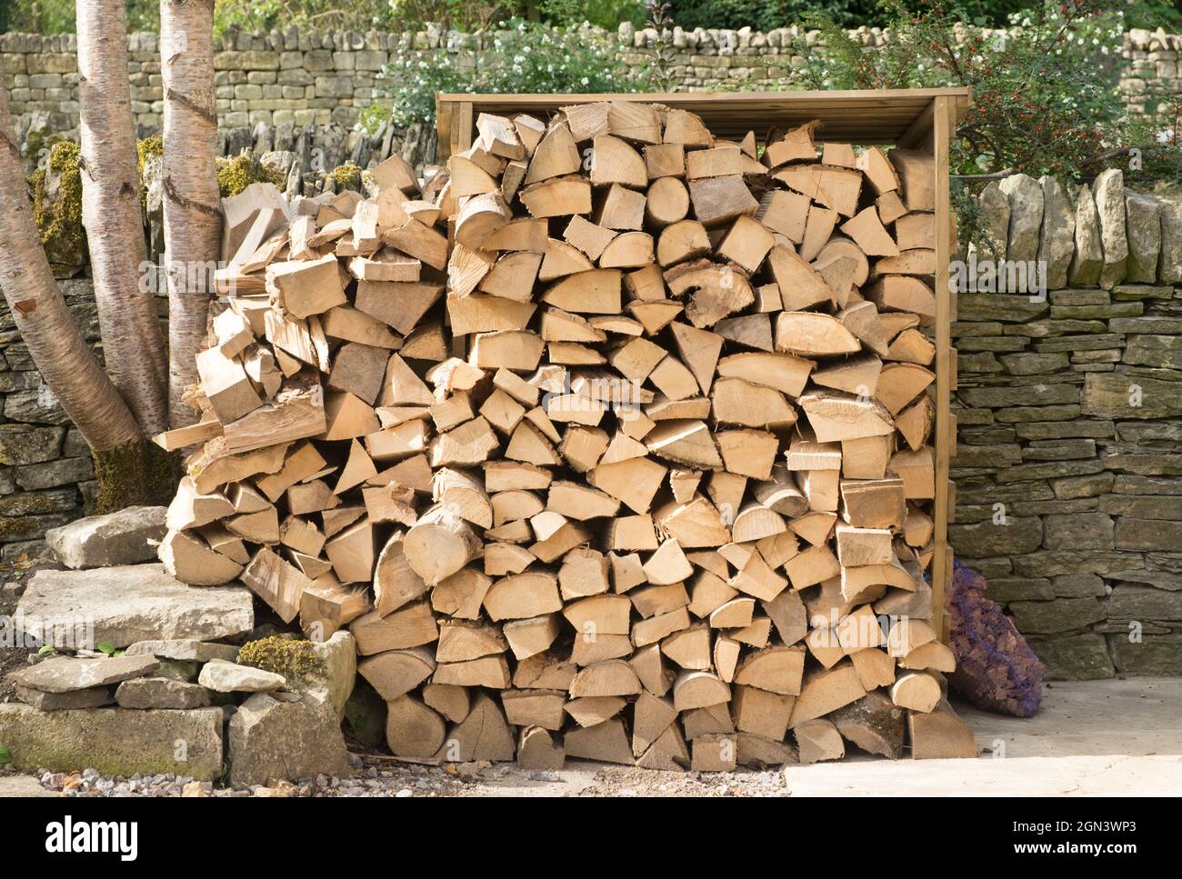 Blick auf Guiting Power, ein cotswold Village in Gloucestershire. Baumstämme würzen in einem Hüttengarten Stockfoto