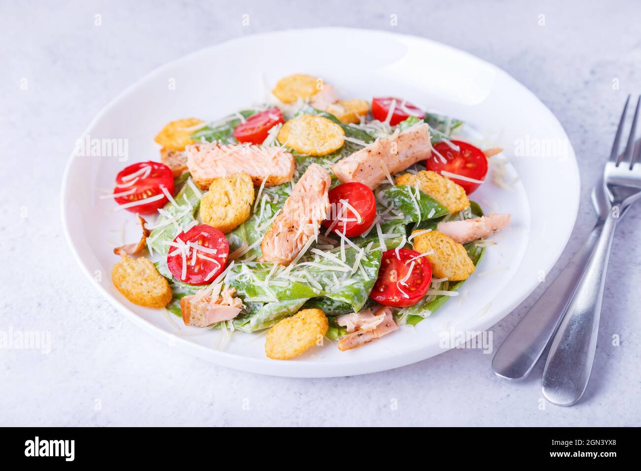 Caesar-Salat mit rotem Fisch (Lachs, Forelle), Kirschtomaten, Croutons, Parmesan-Käse und Romaine. Traditionelles amerikanisches Gericht. Nahaufnahme, selektiver FOC Stockfoto