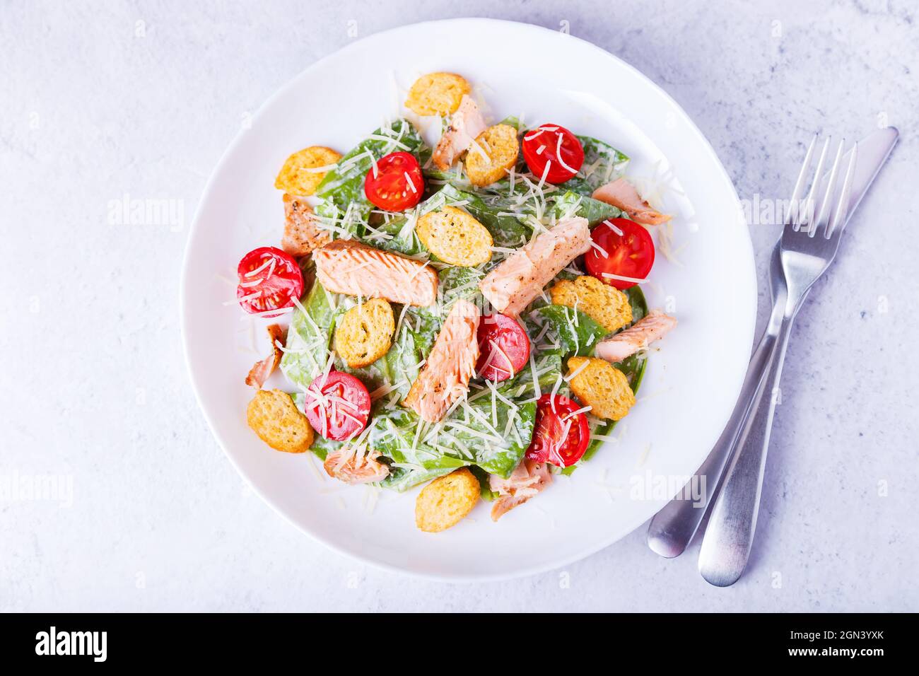 Caesar-Salat mit rotem Fisch (Lachs, Forelle), Kirschtomaten, Croutons, Parmesan-Käse und Romaine. Traditionelles amerikanisches Gericht. Nahaufnahme, selektiver FOC Stockfoto