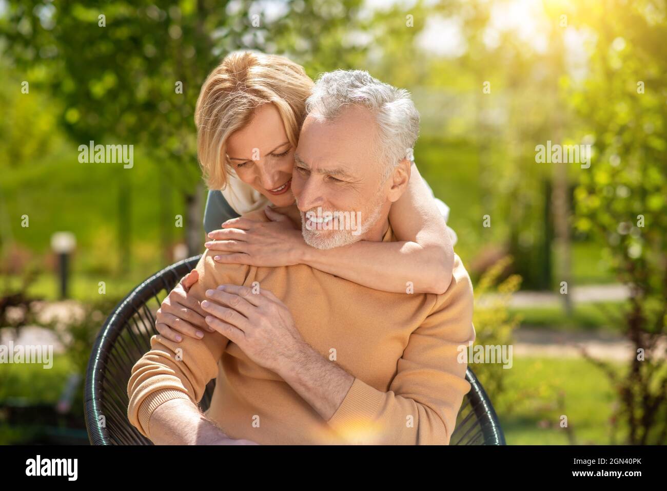 Zufriedener Mann, der von einer Frau von hinten umarmt wird Stockfoto